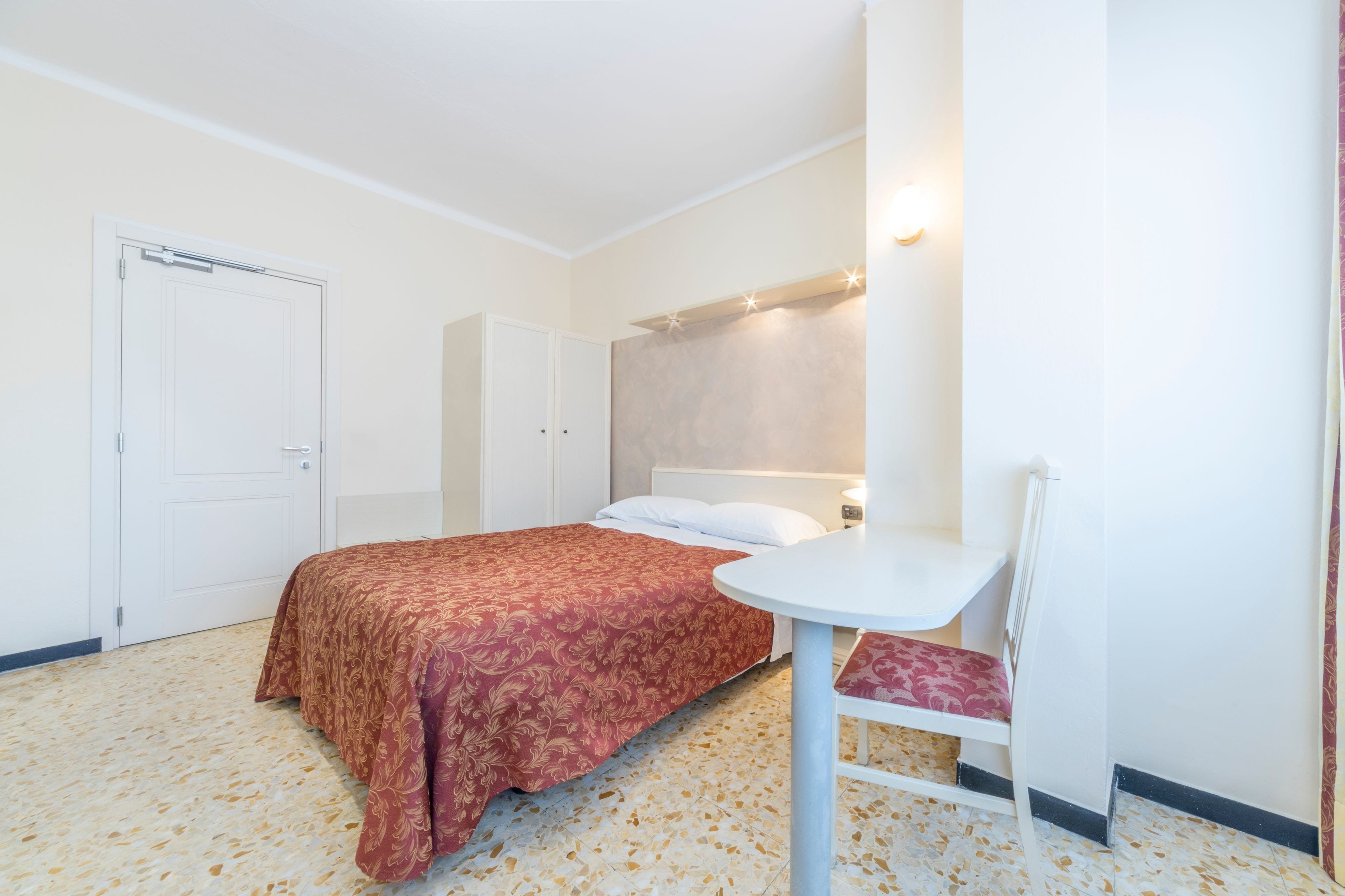 Una habitación de hotel con una cama, una mesita y una silla.