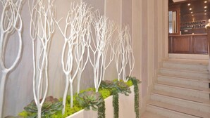 Un interno moderno con una scala e un pannello decorativo con sculture astratte bianche e piante verdi.