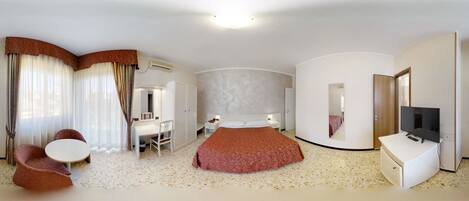 A modern hotel room with a bed, a desk, a chair, a TV, and a mirror.