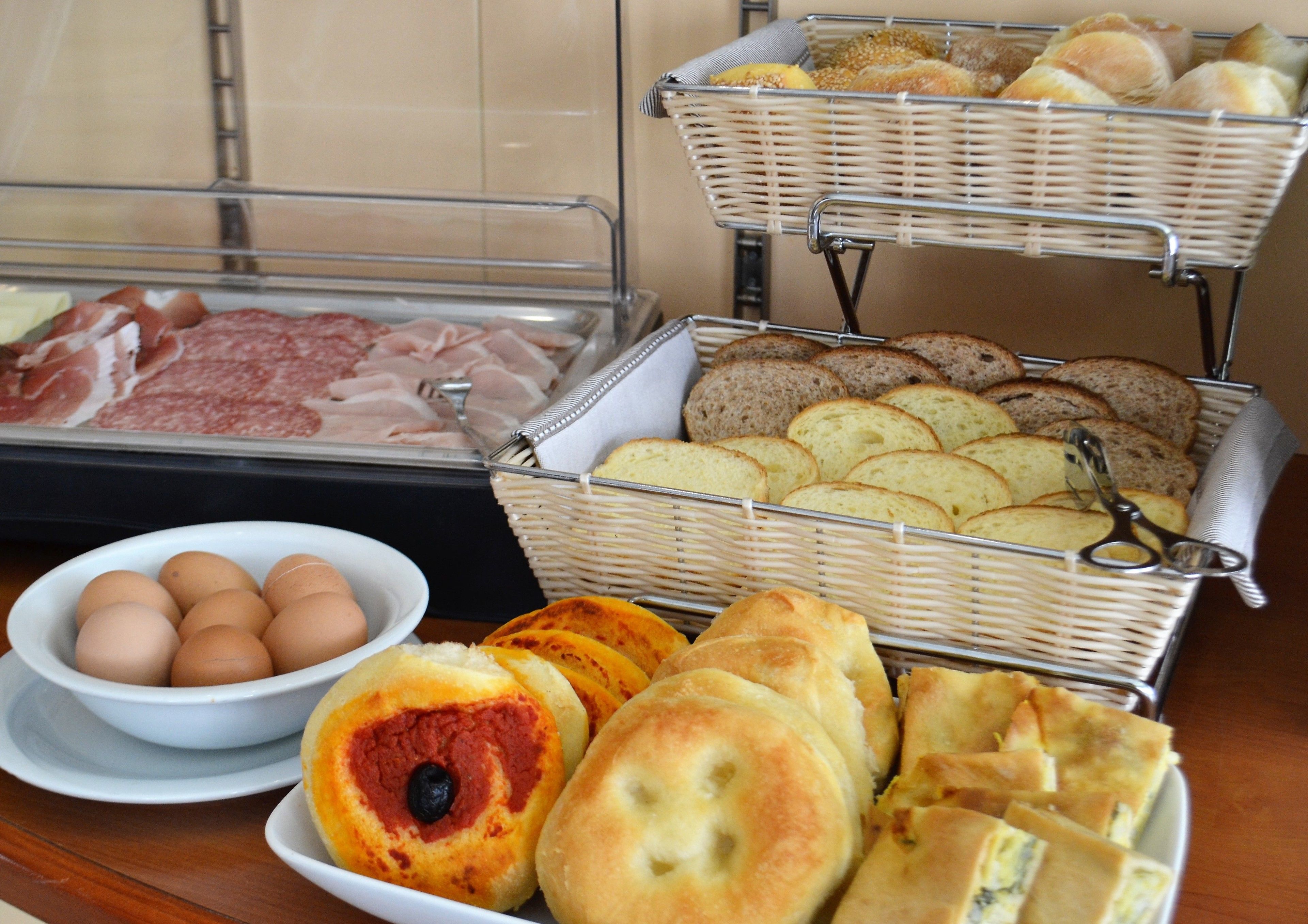 Un ricco buffet per la colazione con pane, dolci, uova e salumi.
