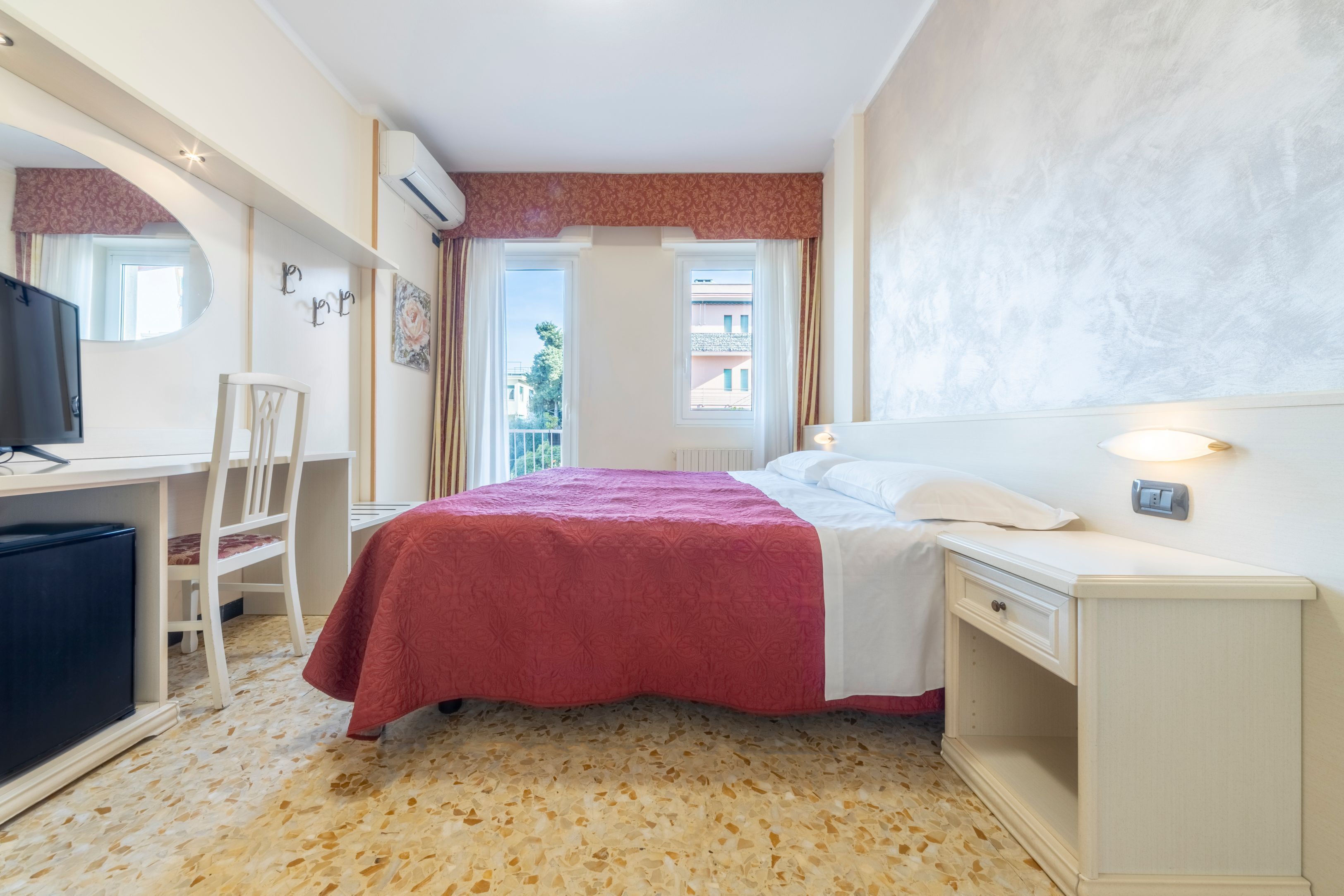 A hotel room with a bed, a desk, a chair, and a TV.