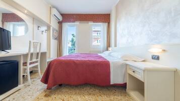 Une chambre d’hôtel avec un lit, un bureau, une chaise et un téléviseur.