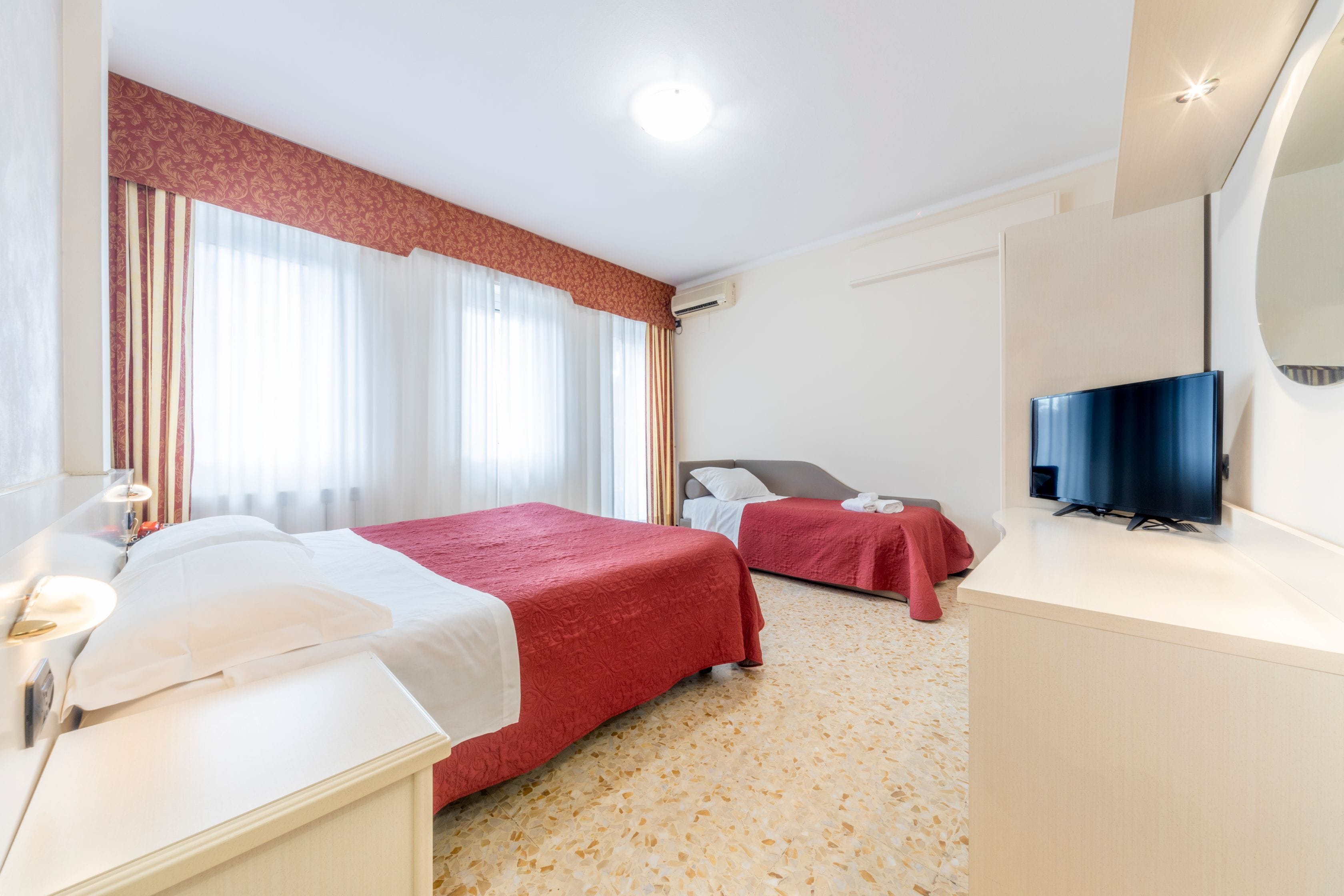 Una habitación de hotel con dos camas, televisión, escritorio y baño.