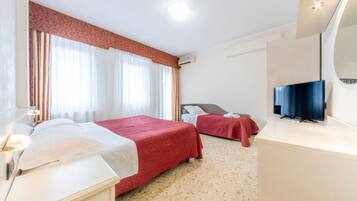 Una habitación de hotel con dos camas, televisión, escritorio y baño.