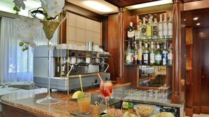Angolo bar con una macchina per caffè, un bicchiere di tè freddo, un bicchiere da martini e diverse bottiglie sugli scaffali.