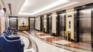 A modern lobby with a curved seating area, elevators, and a reception desk. - MADEN Hotel-مادن (Madinah)