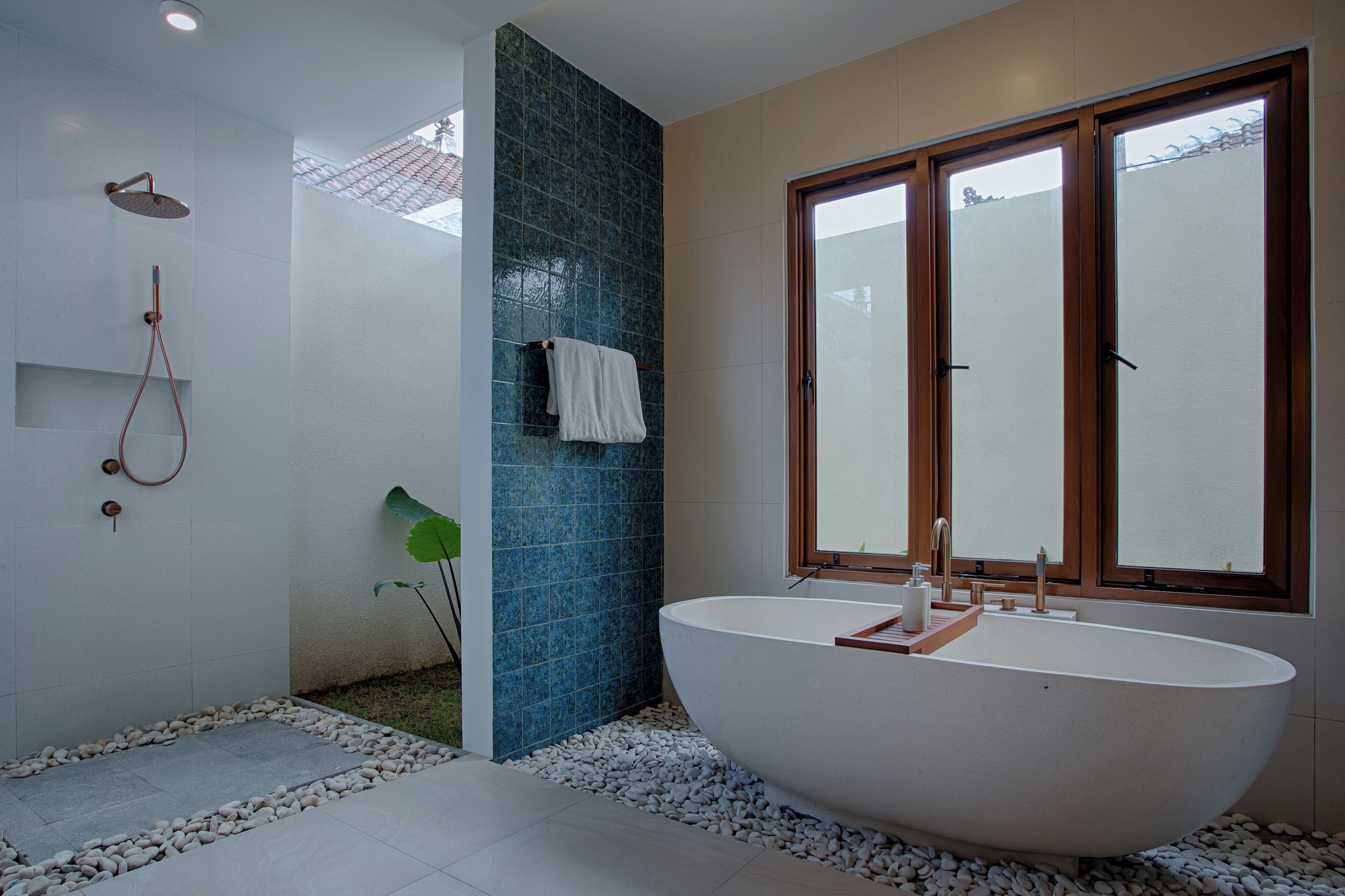 A modern bathroom with a freestanding bathtub, a shower, and a large window.