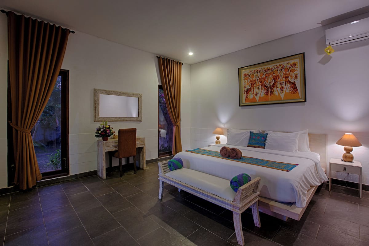Une chambre d’hôtel avec un lit, des tables de chevet, un bureau, une chaise et des rideaux.