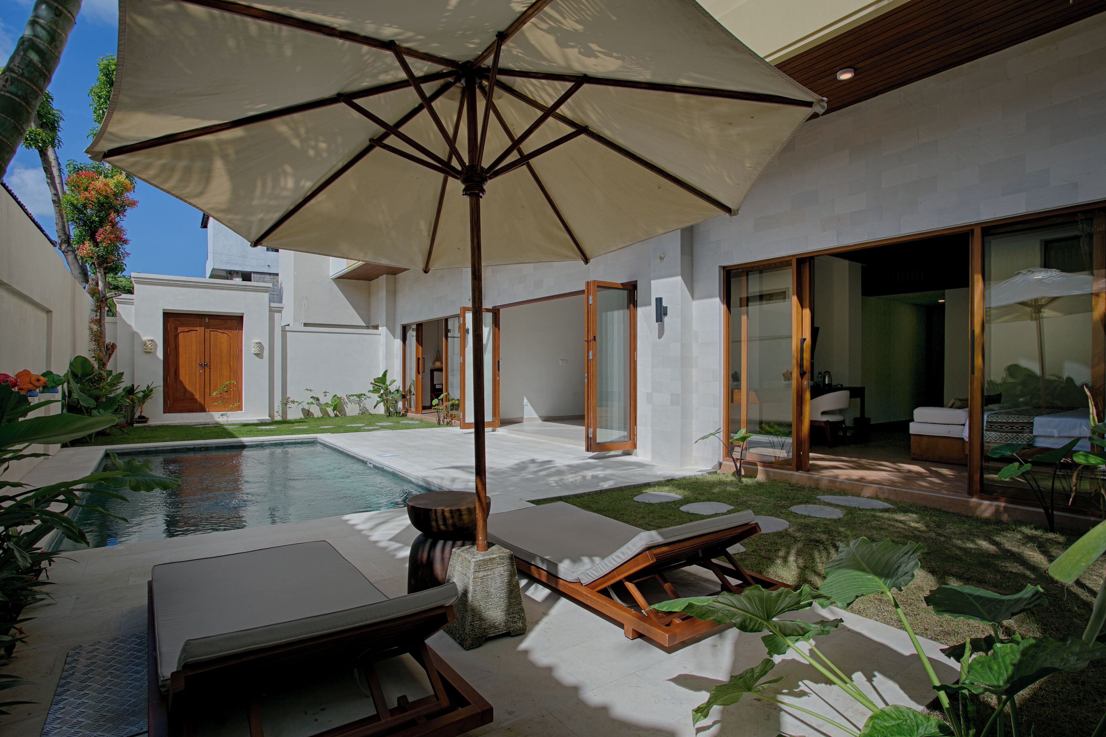 A modern outdoor pool area with lounge chairs and a large umbrella.