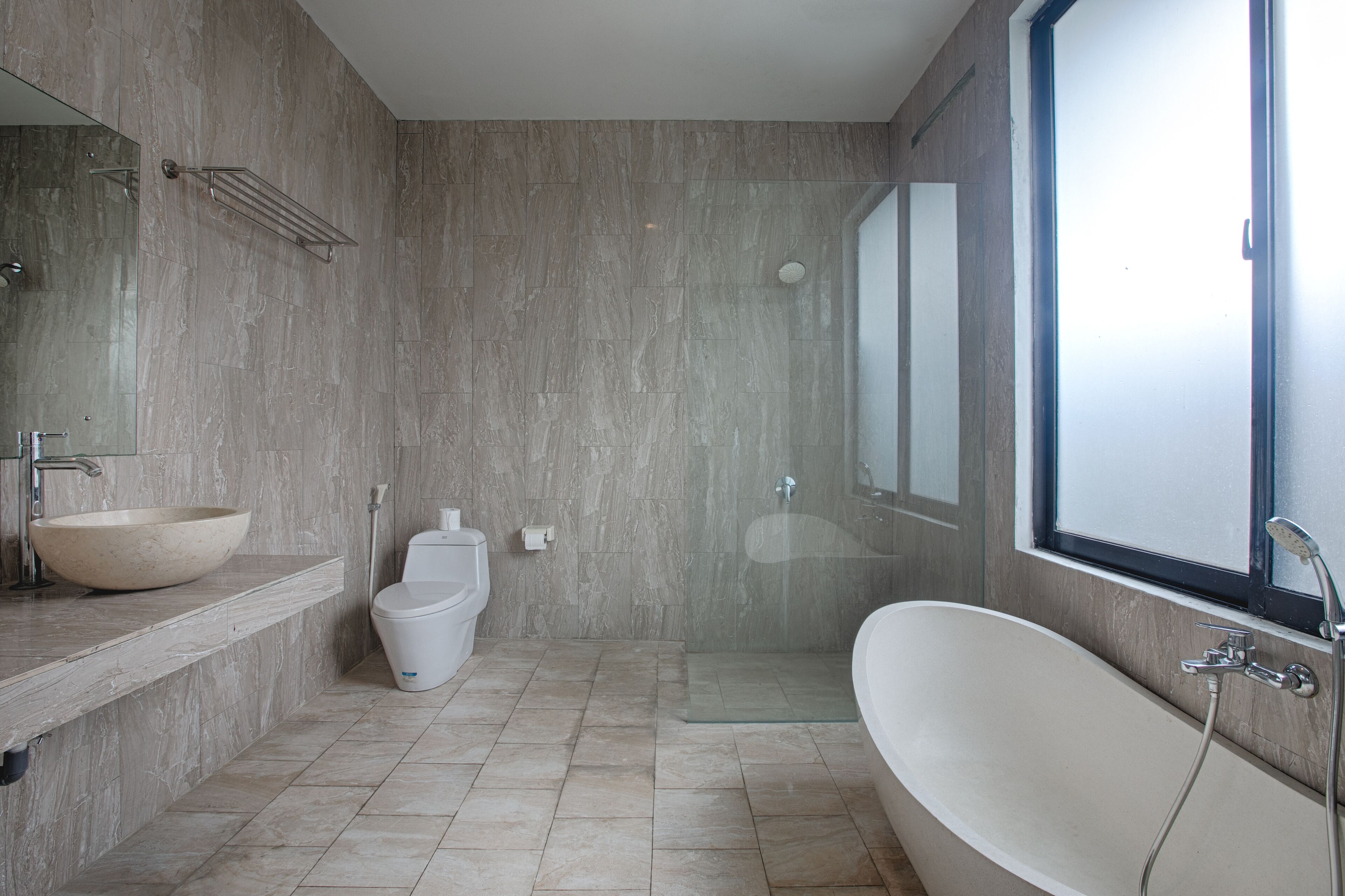 A modern bathroom with a freestanding bathtub, a glass-enclosed shower, a toilet, and a large mirror.