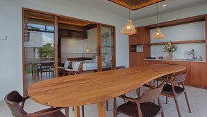 A modern kitchen with wooden cabinets, a large wooden dining table, and pendant lights.