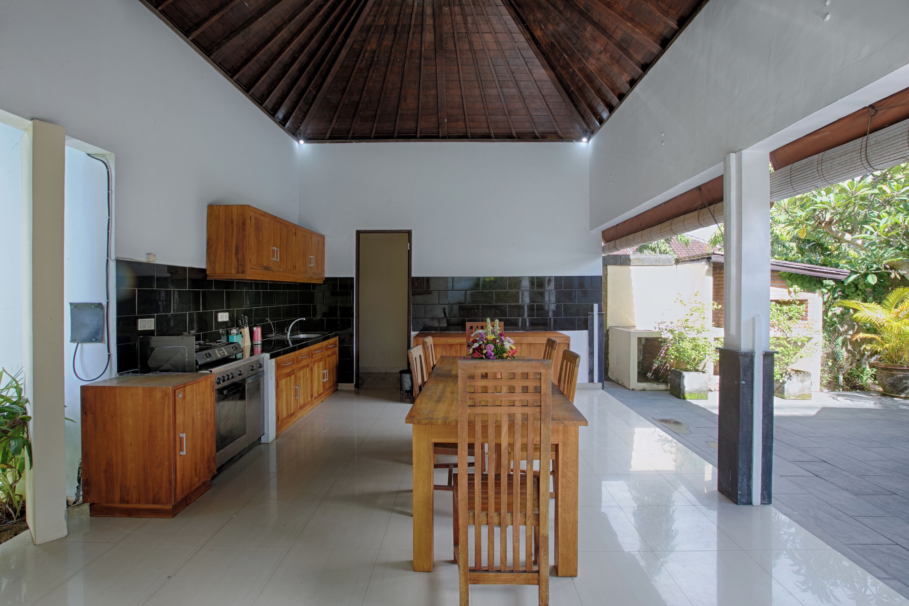 Una cocina moderna con armarios de madera, una isla central y un comedor con mesa y sillas de madera.