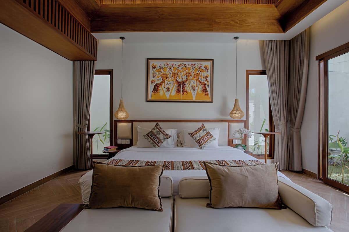 Une chambre spacieuse avec un grand lit, deux tables de chevet, une commode et une fenêtre avec des rideaux.