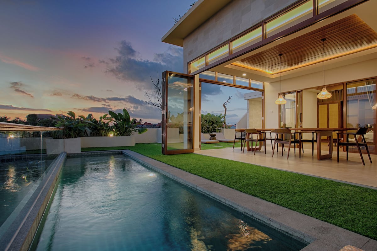 Une maison moderne dotée d’une piscine, de portes vitrées et d’un coin repas.