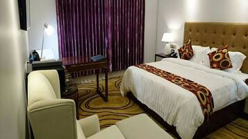 Una habitación de hotel con una cama grande, un escritorio, una silla y una lámpara.