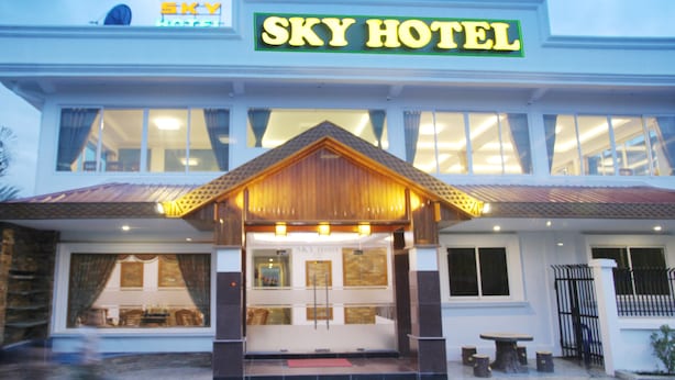 El exterior del HOTEL SKY con un cartel llamativo, ventanas amplias y un toldo de madera en la entrada.