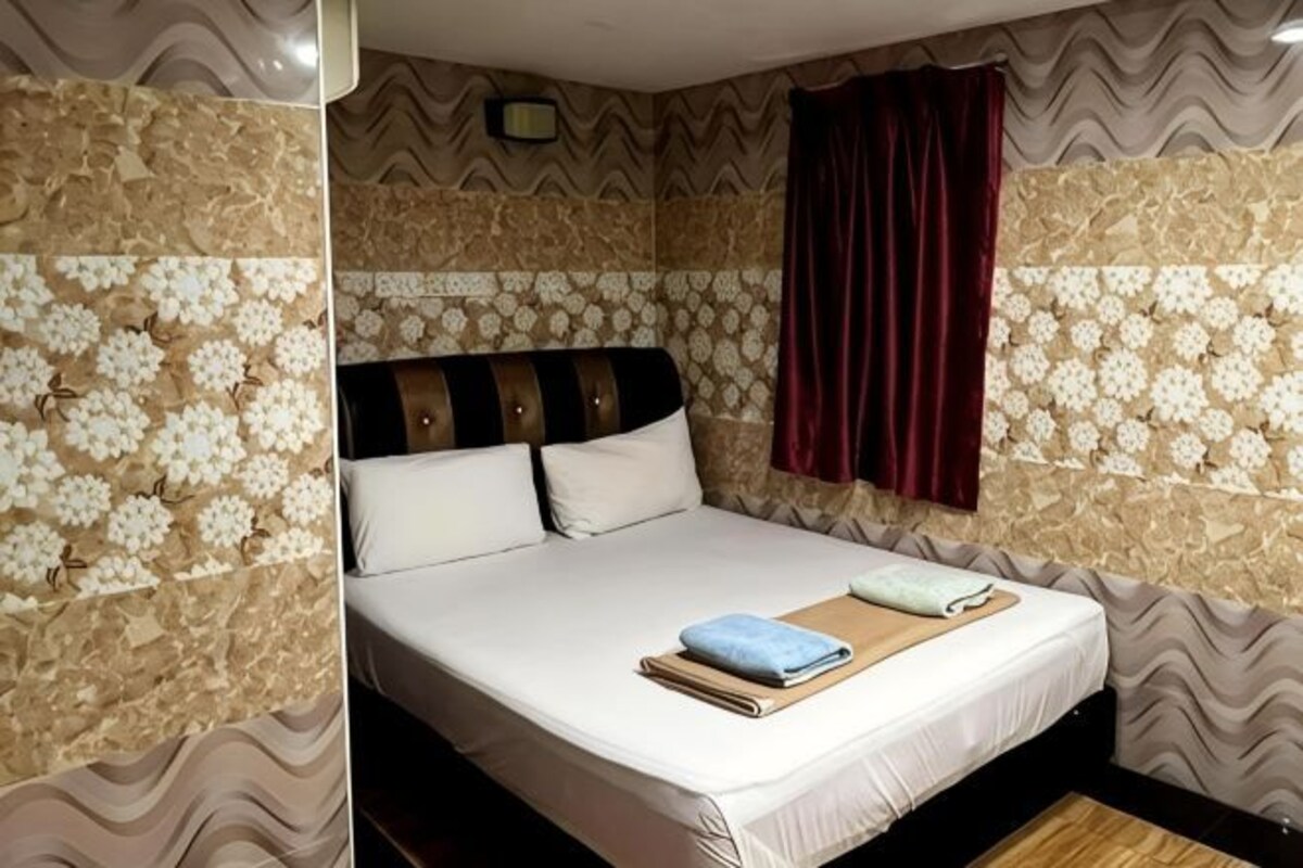 A bed with a headboard, a bedside table, and a window with curtains.