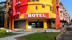 Um hotel com fachada curva, unidades de ar condicionado e entrada visível.