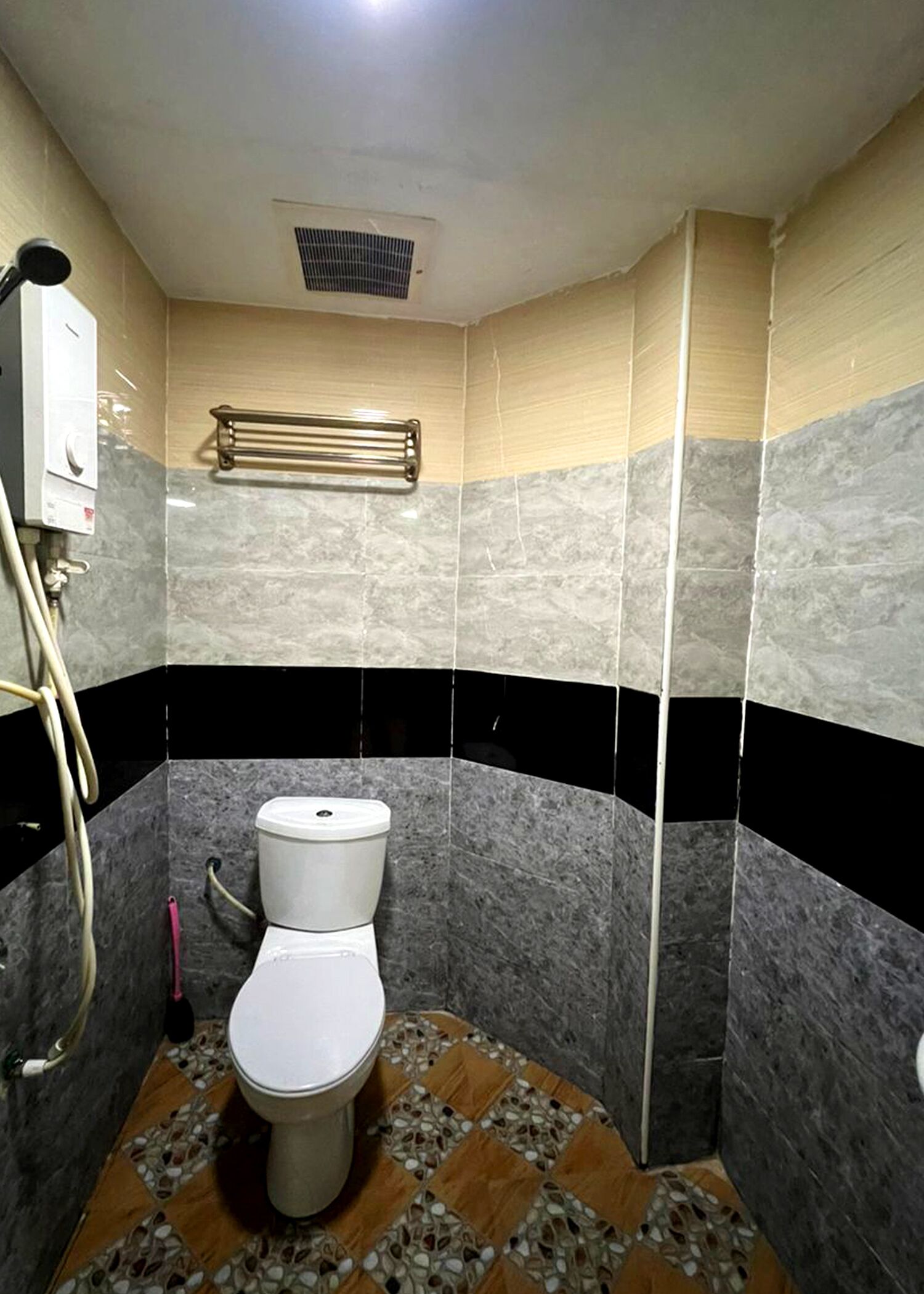 A bathroom with a toilet, a shower area, and a towel rack.