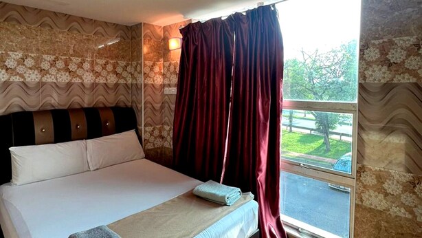 Quarto de hotel com uma cama grande, janela com cortinas e vista para o exterior.