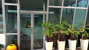 A building entrance with glass doors, potted plants, and a yellow vase. - Banana Place Resort (Chumphon)