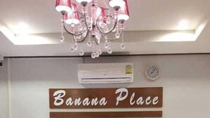 A living room with a sofa, coffee table, and a chandelier. A sign on the wall reads "Banana Place." - Banana Place Resort (Chumphon)