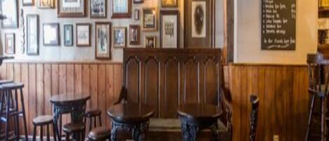 A rustic bar area with wooden furniture, framed pictures on the walls, and a menu board.