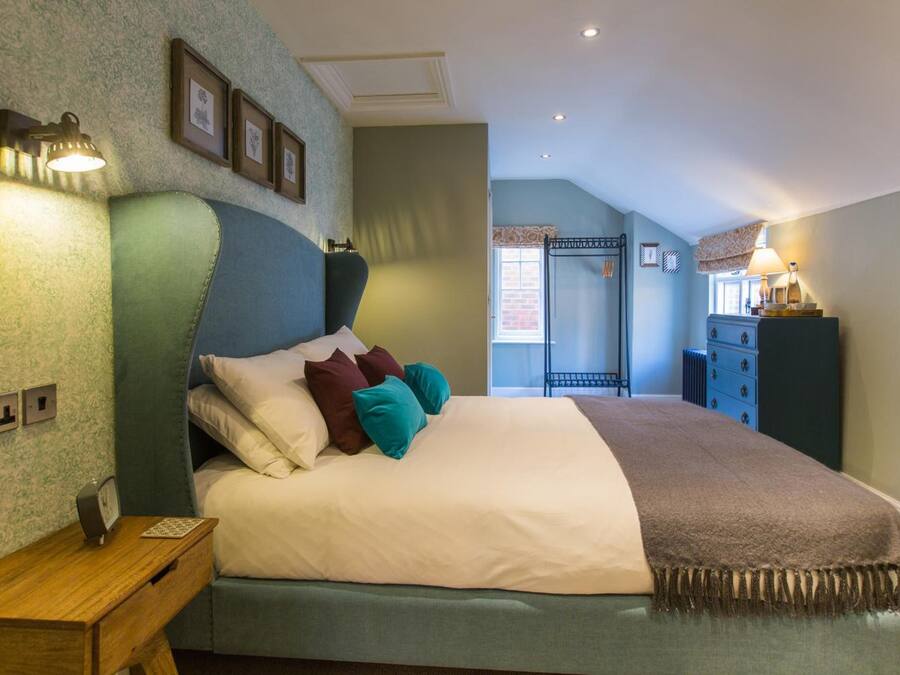 Een netjes ingerichte slaapkamer met een bed, nachtkastje, lamp en uitzicht op een balkon.