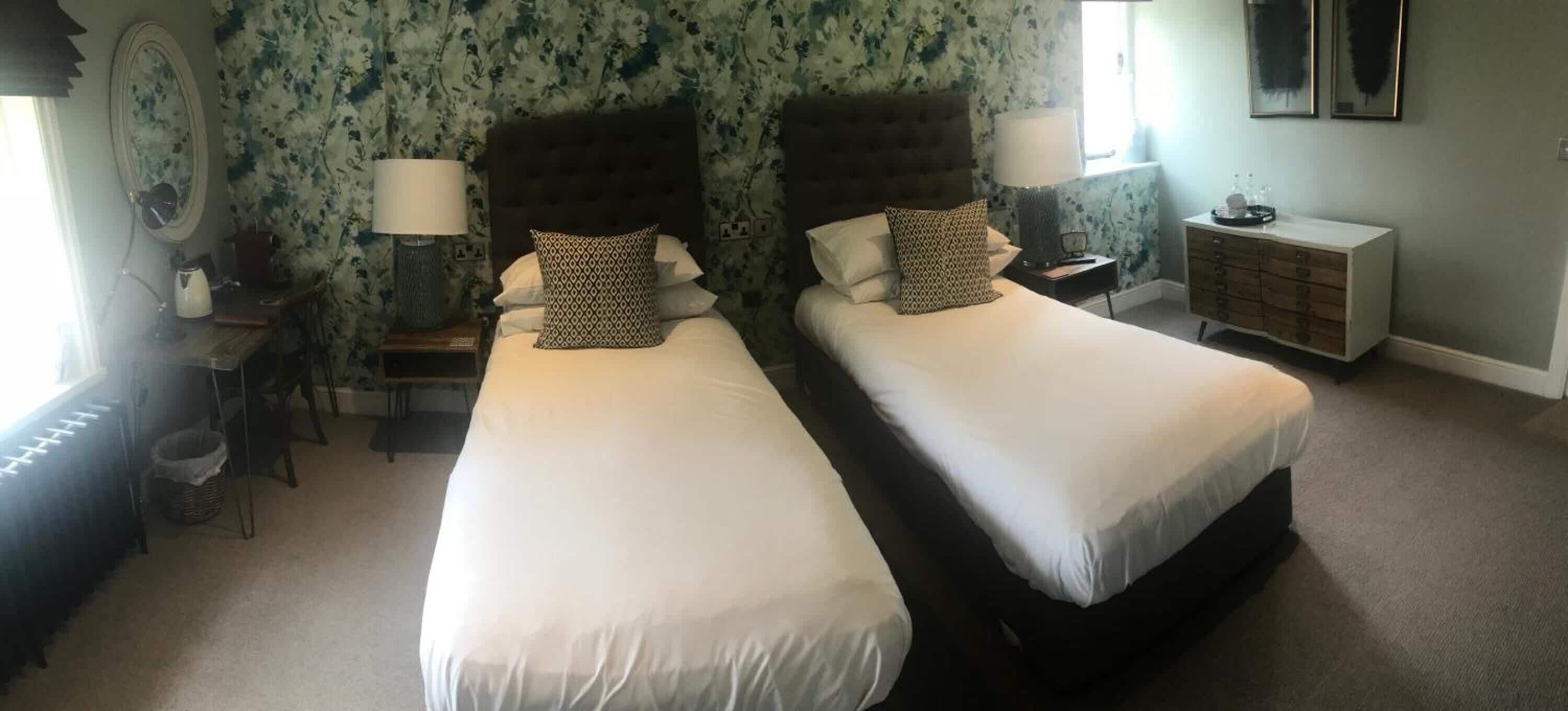 Une chambre d’hôtel avec deux lits, une commode, un bureau et une chaise.