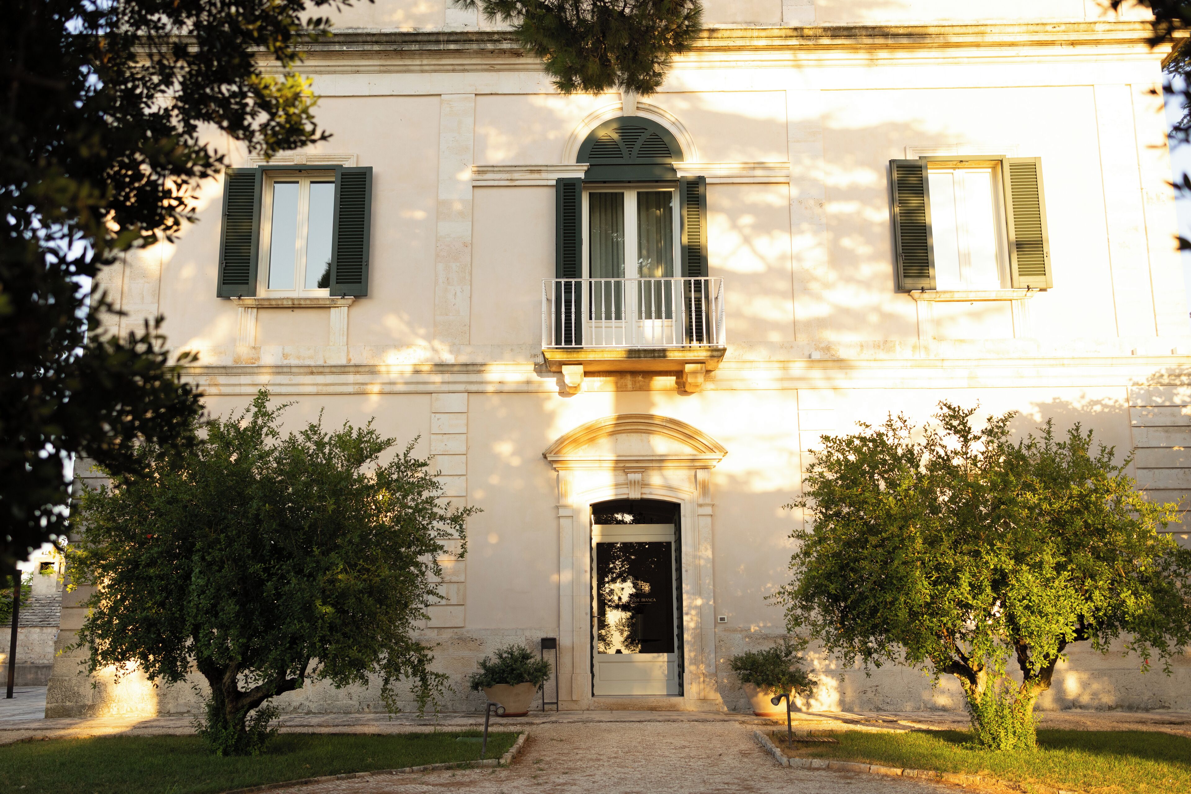 A building with a central entrance, two windows with shutters, and a small balcony.