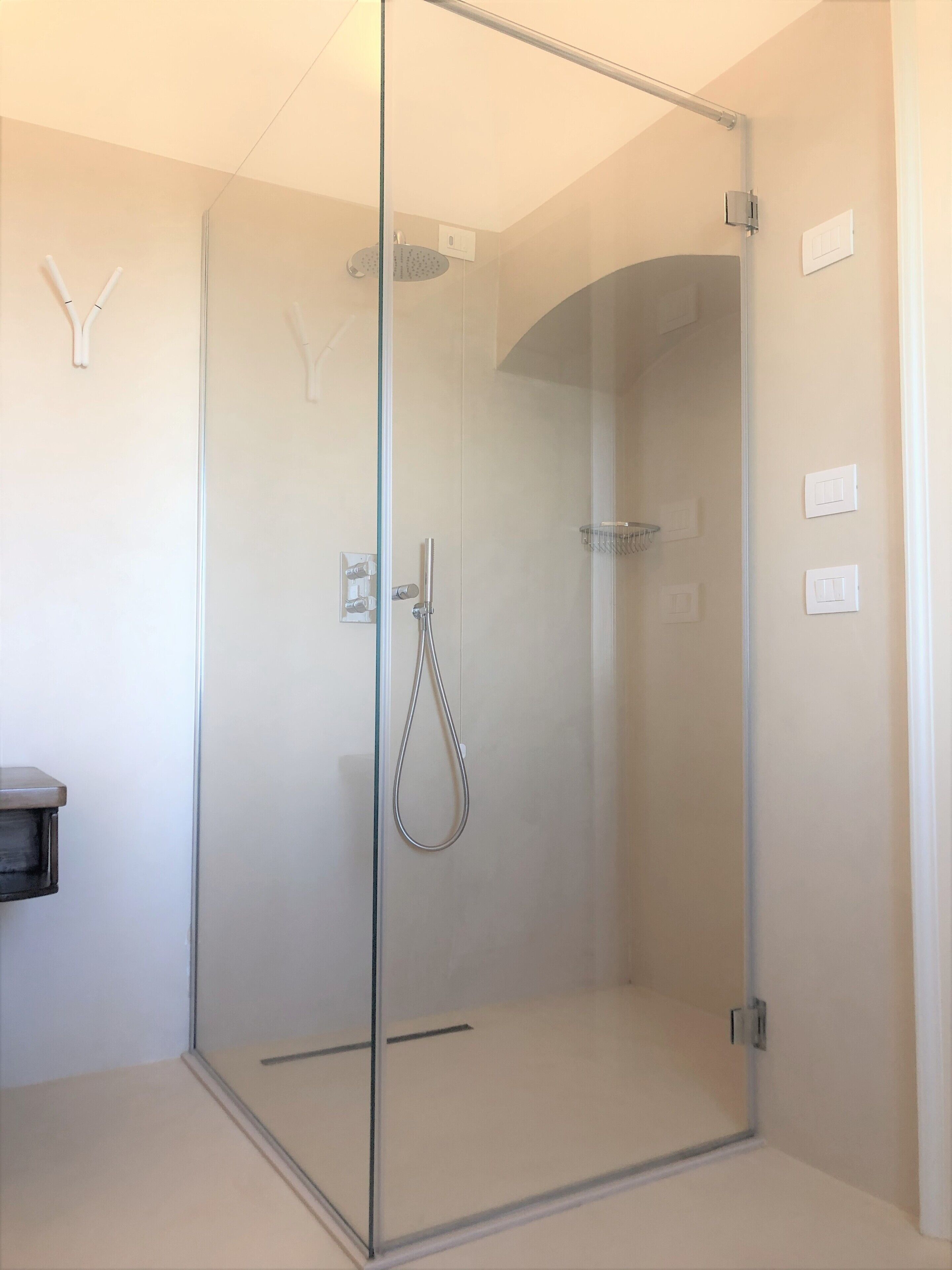 A modern bathroom with a glass-enclosed shower, a toilet, and a sink.