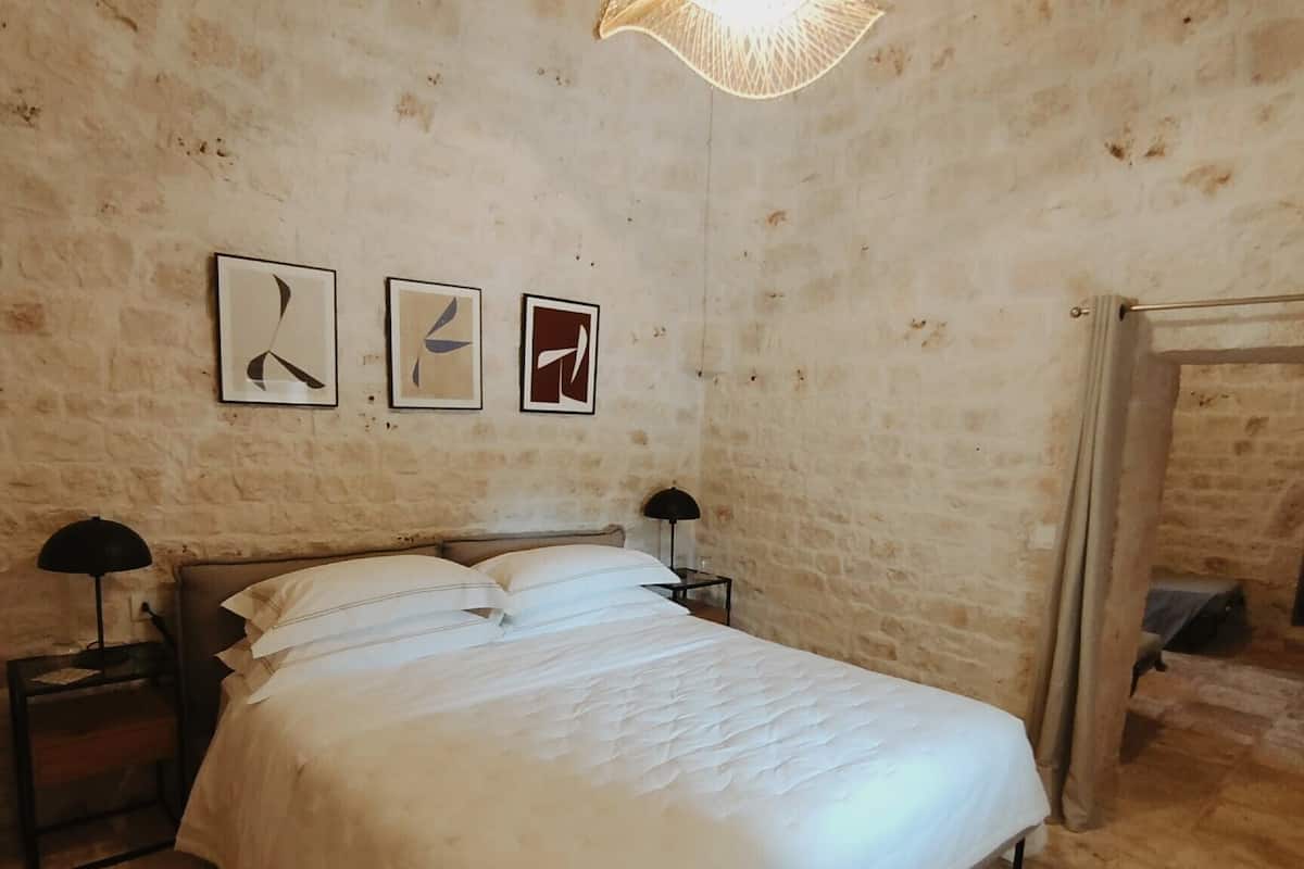 A bedroom with a large bed, a nightstand, a lamp, and three framed pictures on the wall.