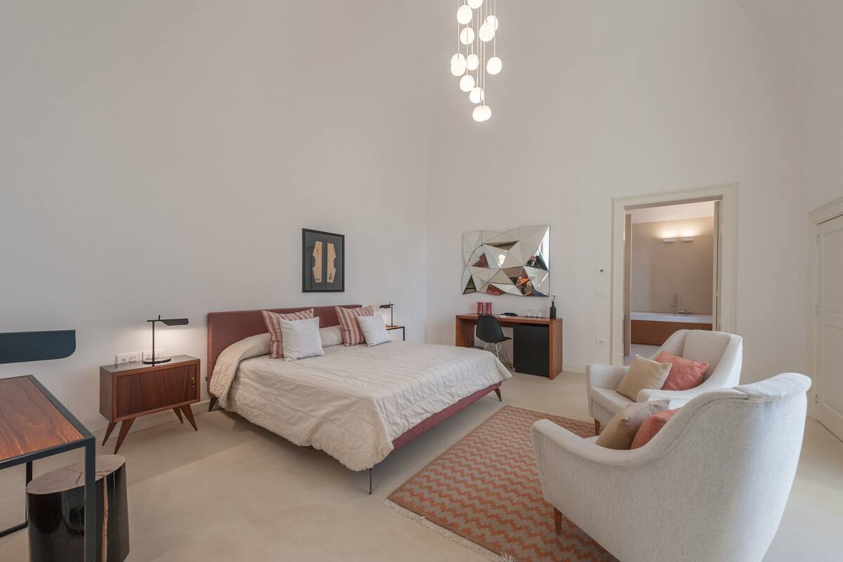 A modern bedroom with a bed, desk, chair, and a small table.