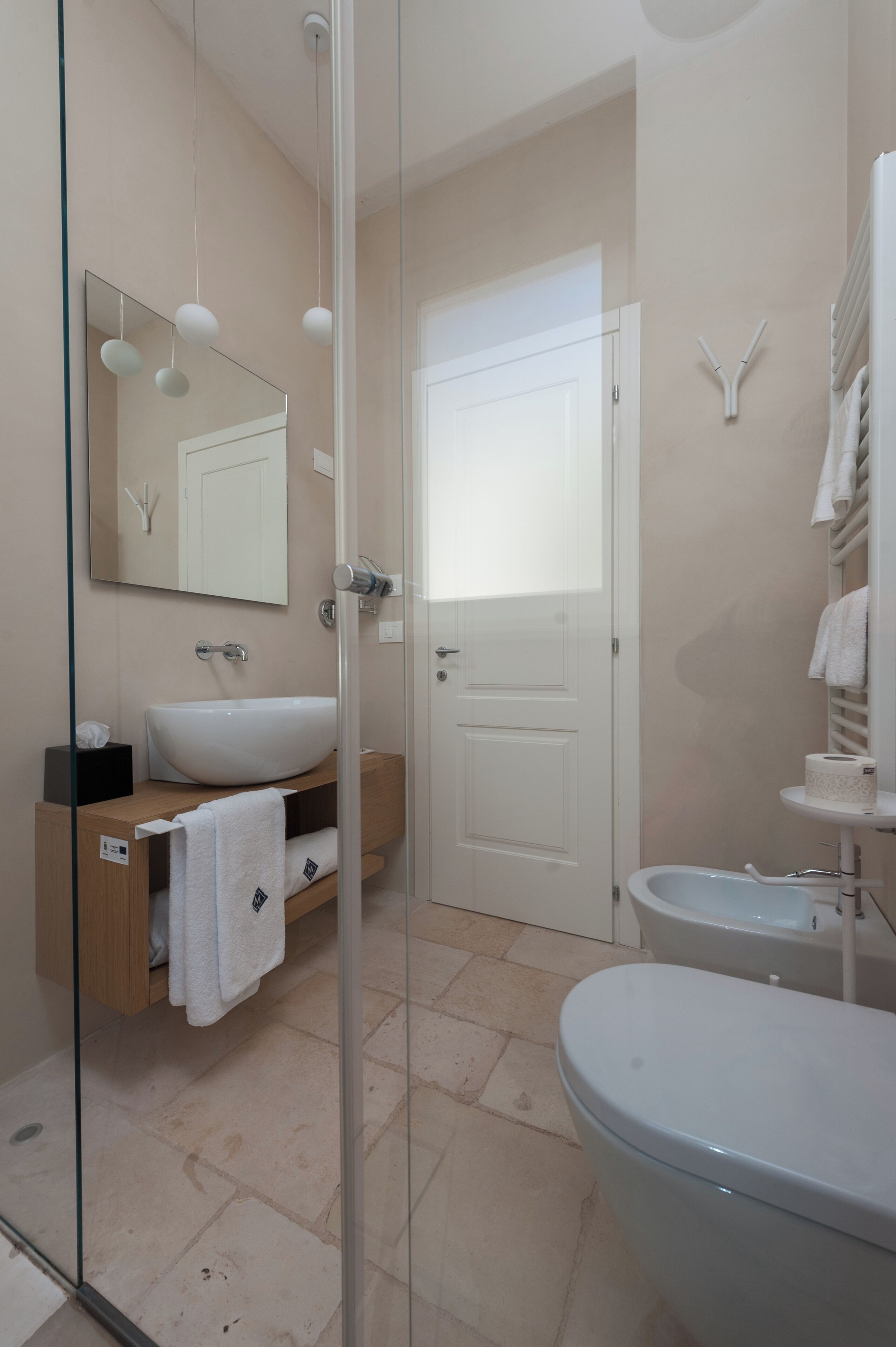 Un baño moderno con cabina de ducha de vidrio, un lavabo blanco y un inodoro.