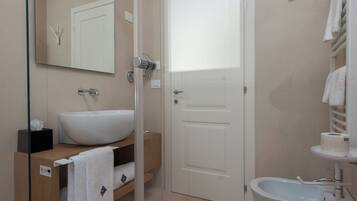 Un baño moderno con cabina de ducha de vidrio, un lavabo blanco y un inodoro.
