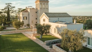 A large, white building with a tower, surrounded by a well-maintained lawn and stone walls. - Villa Torre Bianca by Emily Hotels (Polignano a Mare)