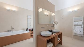 Ein modernes Badezimmer mit einer großen Badewanne, zwei Waschbecken und einem Waschtisch mit Ablageflächen.