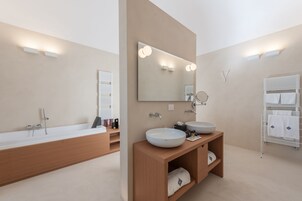 Ein modernes Badezimmer mit einer großen Badewanne, zwei Waschbecken und einem Waschtisch mit Ablageflächen.