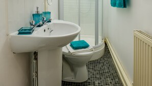 Un baño con lavamanos blanco, inodoro y cabina de ducha de vidrio.