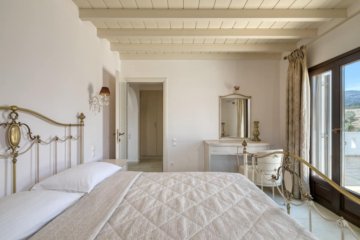A bedroom with a bed, a dresser, a mirror, and a window with curtains.