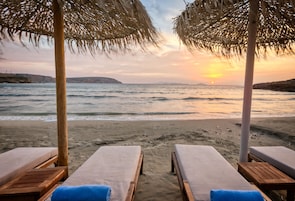 Na praia, espreguiçadeiras, guarda-sóis 