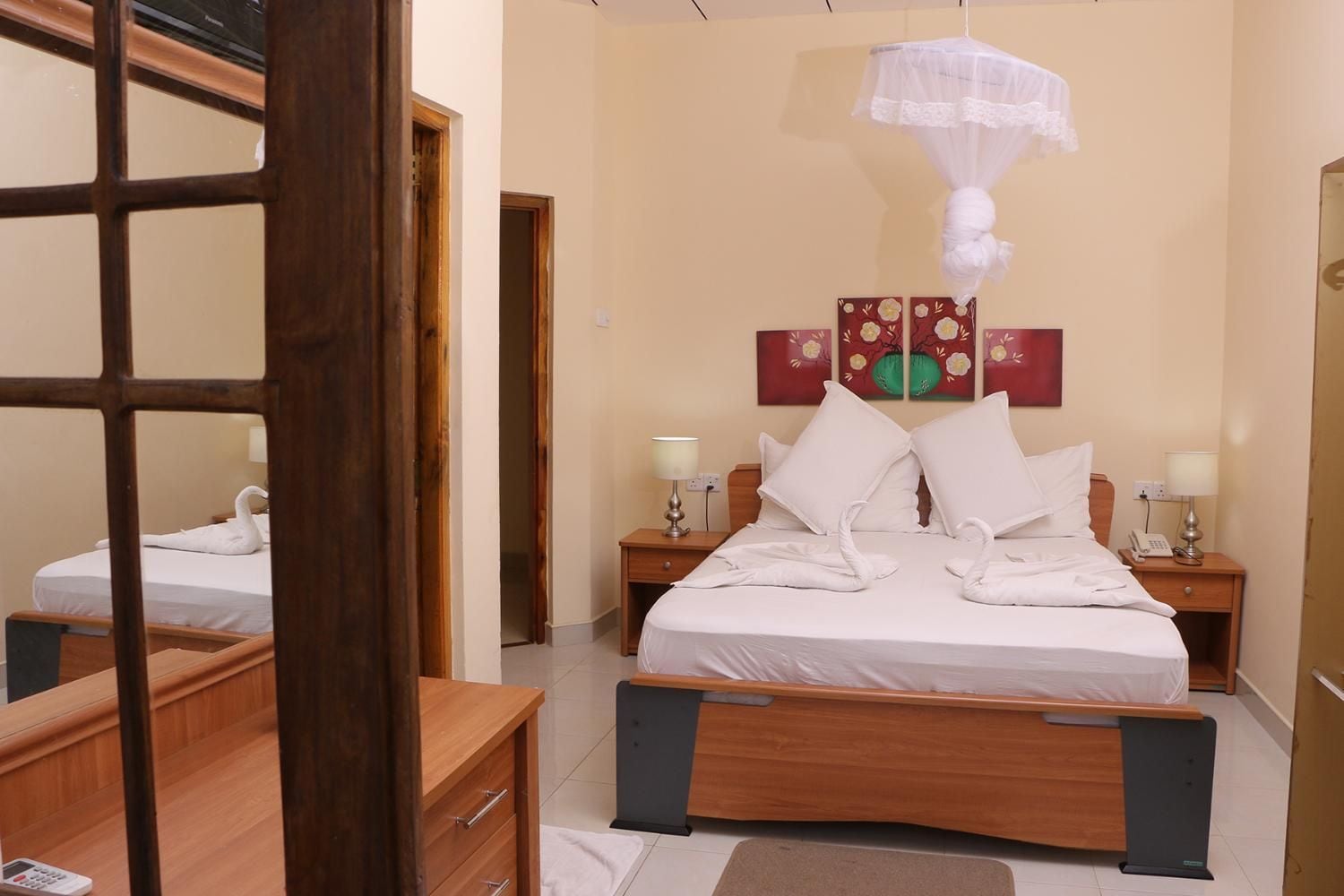Una habitación de hotel con una cama, mesitas de noche, un teléfono y obras de arte en la pared.