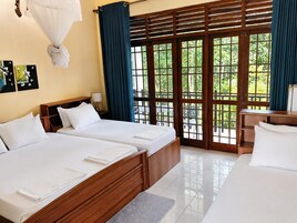 Habitación de hotel con dos camas, una ventana con vistas a zonas verdes y un escritorio de madera.