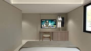 A modern bedroom with a bed, a desk, and a TV mounted on the wall.