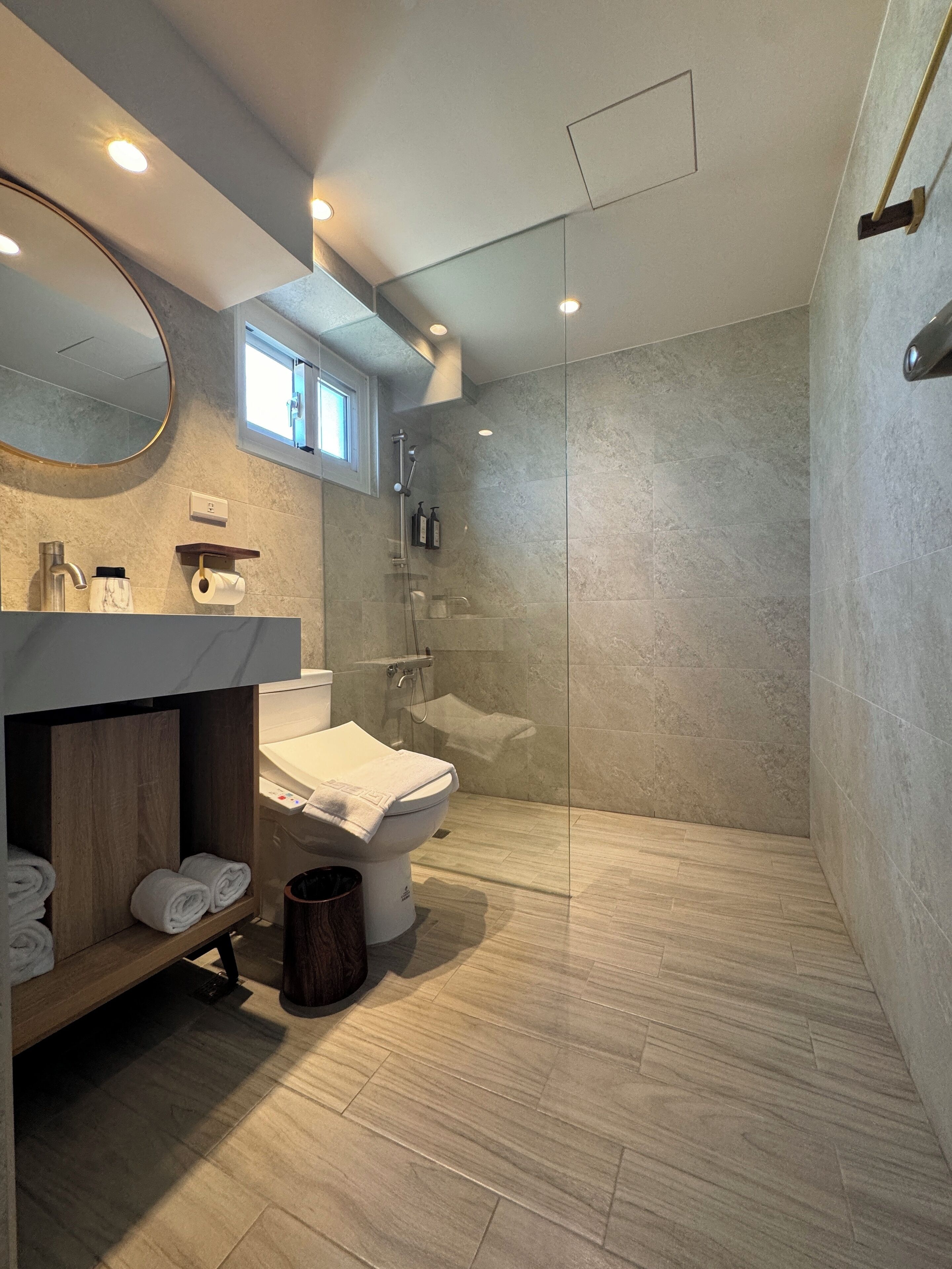 Un baño moderno con ducha envuelta en vidrio, inodoro y tocador con espejo.