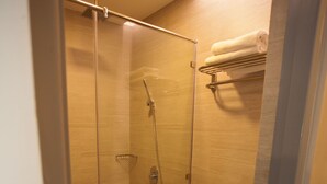 A modern bathroom with a glass-enclosed shower, a toilet, and a towel rack.