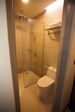 A modern bathroom with a glass-enclosed shower, a toilet, and a towel rack.