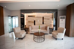 A modern lobby with a marble floor, a sofa, two armchairs, and a coffee table.