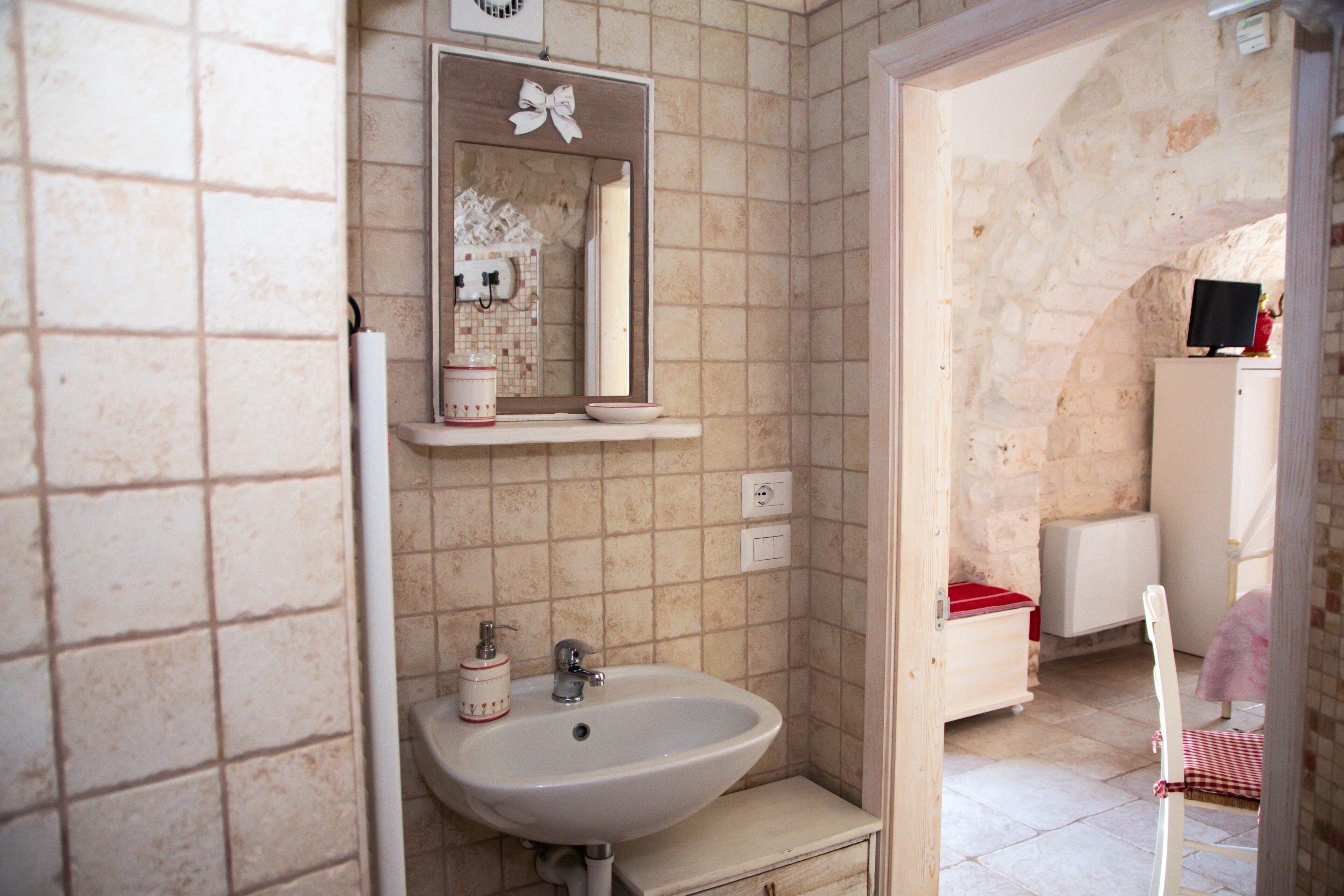 A bathroom with a sink, mirror, and tiled walls.