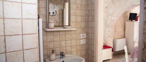 A bathroom with a sink, mirror, and tiled walls.